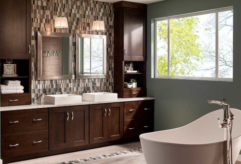 Modern bathroom with dark wood vanity, double sinks, and a freestanding tub by a bright window