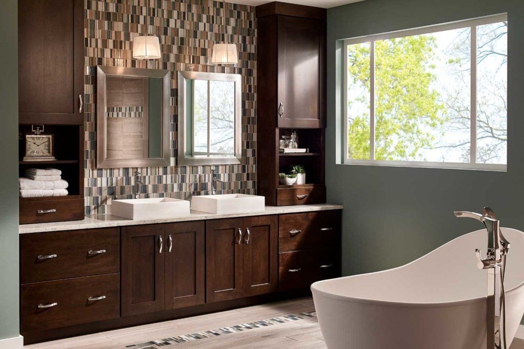 Modern bathroom with dark wood vanity, double sinks, mirrors, and a bathtub beside a bright window