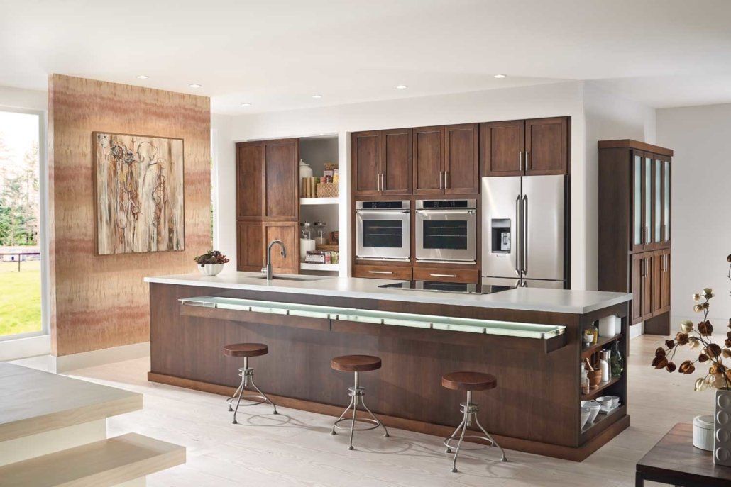 Modern kitchen with dark wood cabinets, stainless steel appliances, and a large island with stools