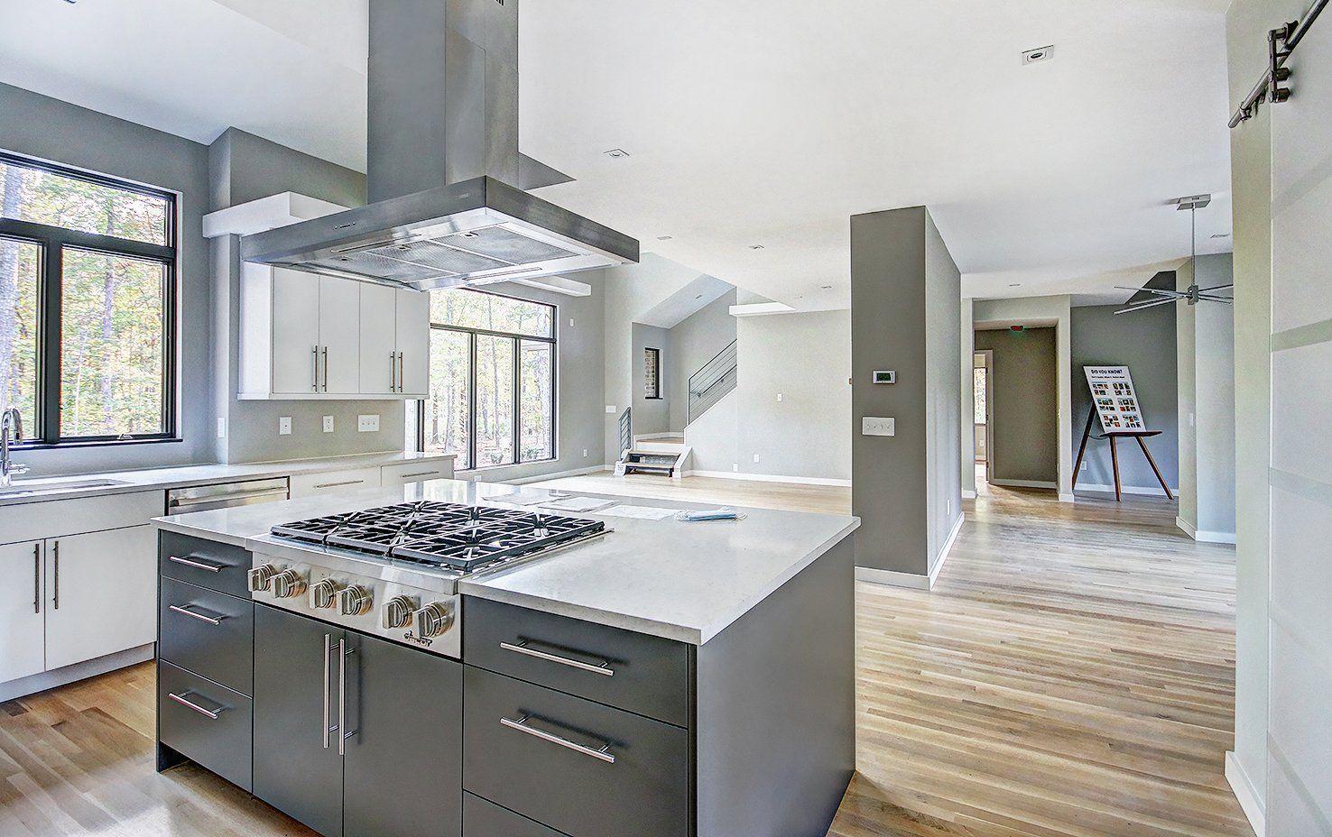 Modern bright kitchen with island, stainless appliances, large windows, and hardwood floors