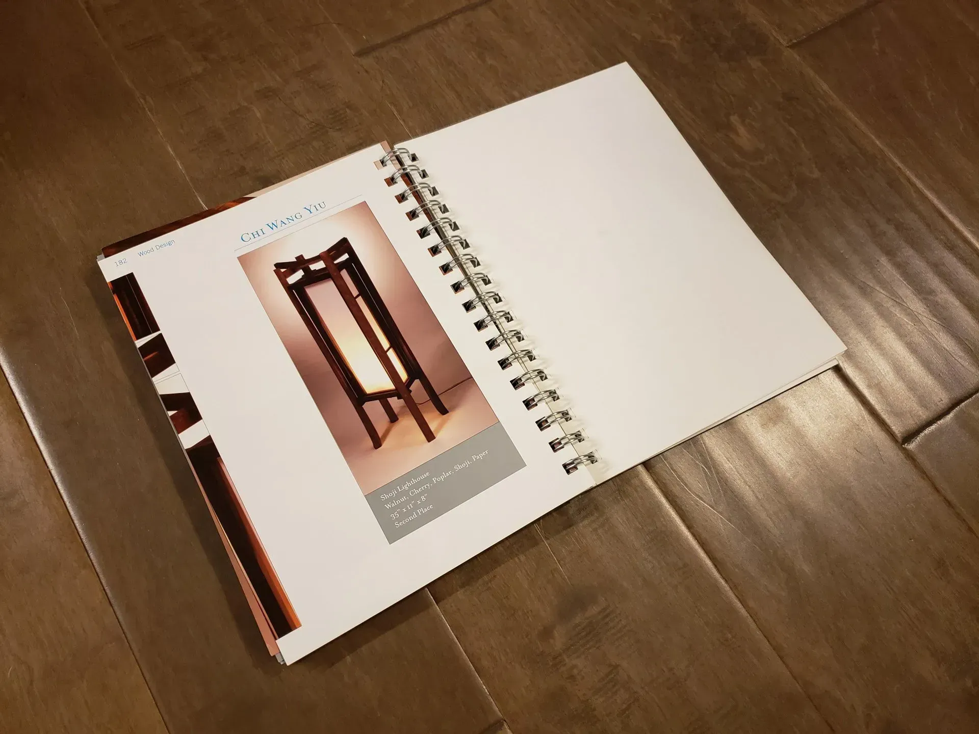 Open spiral-bound notebook on a wooden table, showing a page with a photo and text.