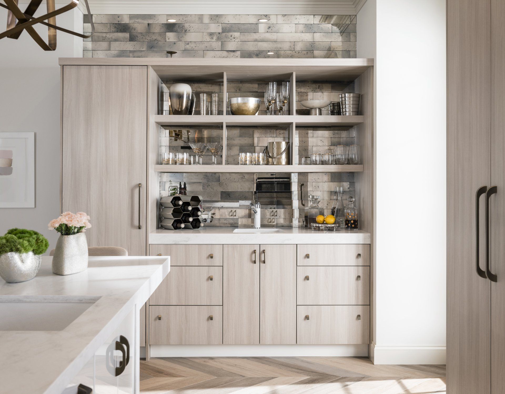 Light wood kitchen hutch with glass shelves, dishes, and decor in a bright modern kitchen