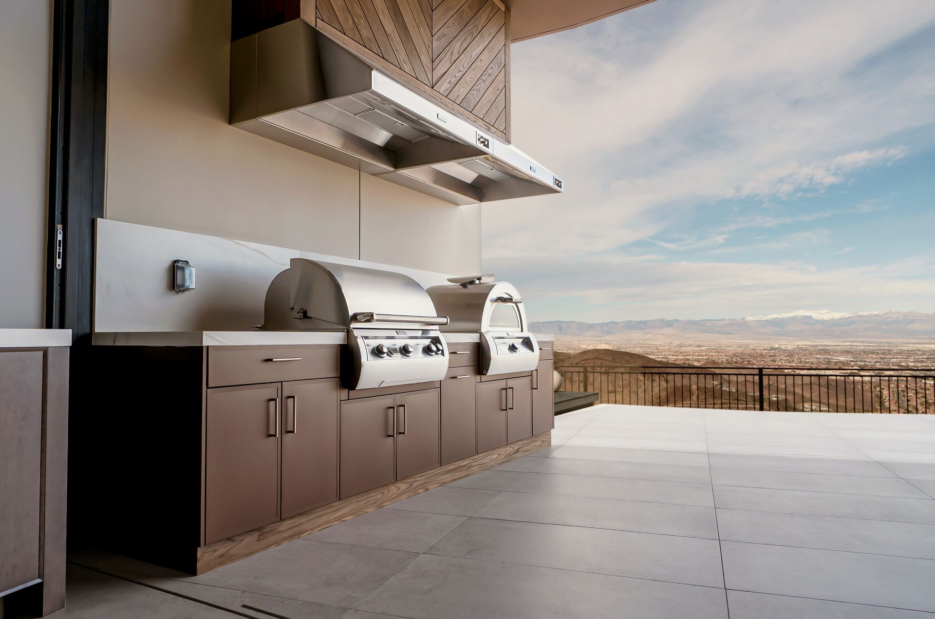 Outdoor patio with built-in grill, cabinets, and a mountain view beyond the railing