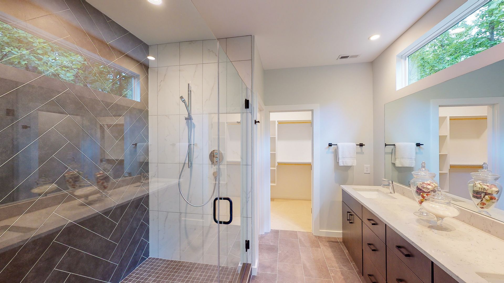 Modern bathroom with glass shower, double vanity, and white walls