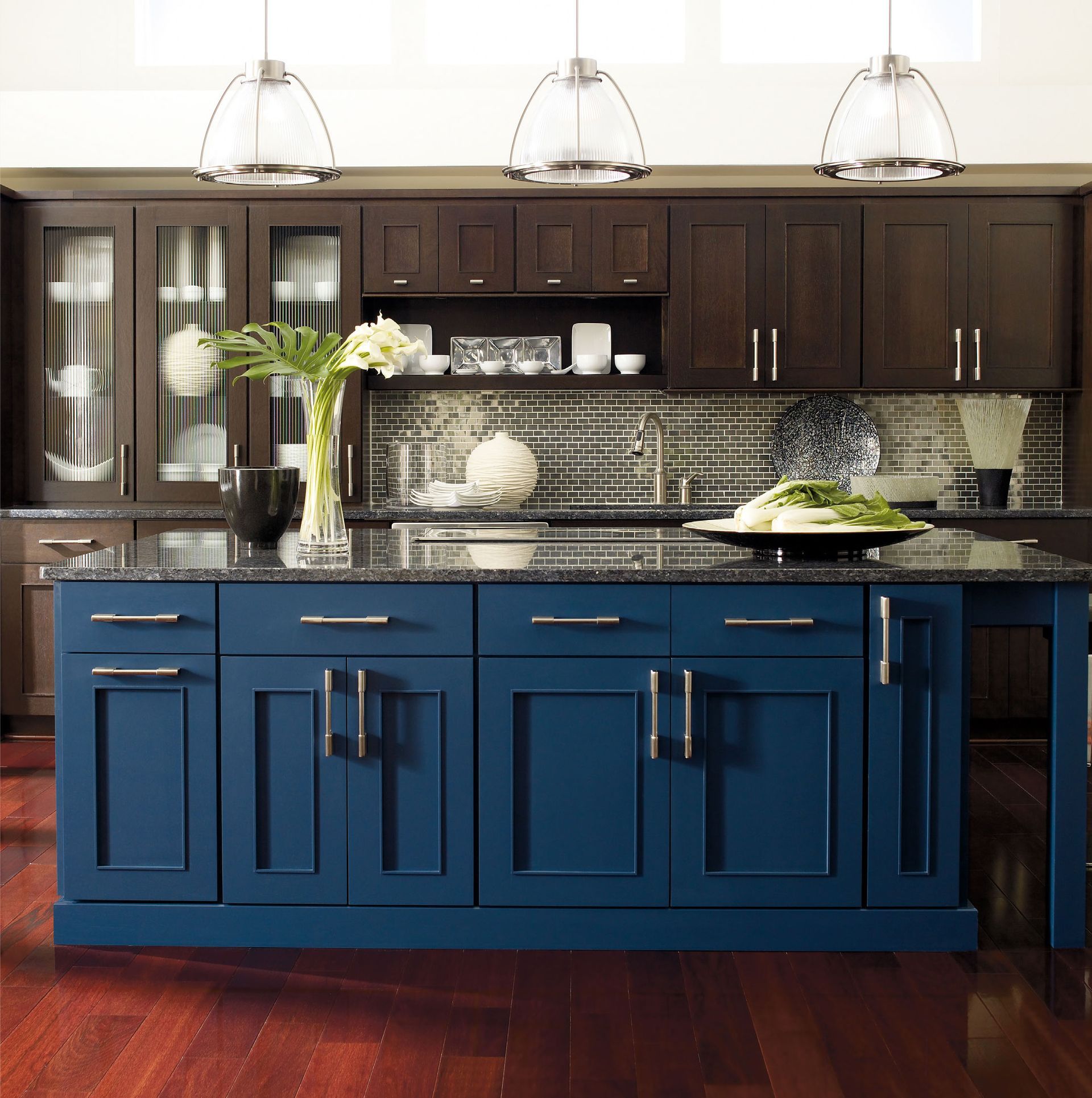 Kitchen with blue island, dark cabinets, granite countertops, and pendant lights