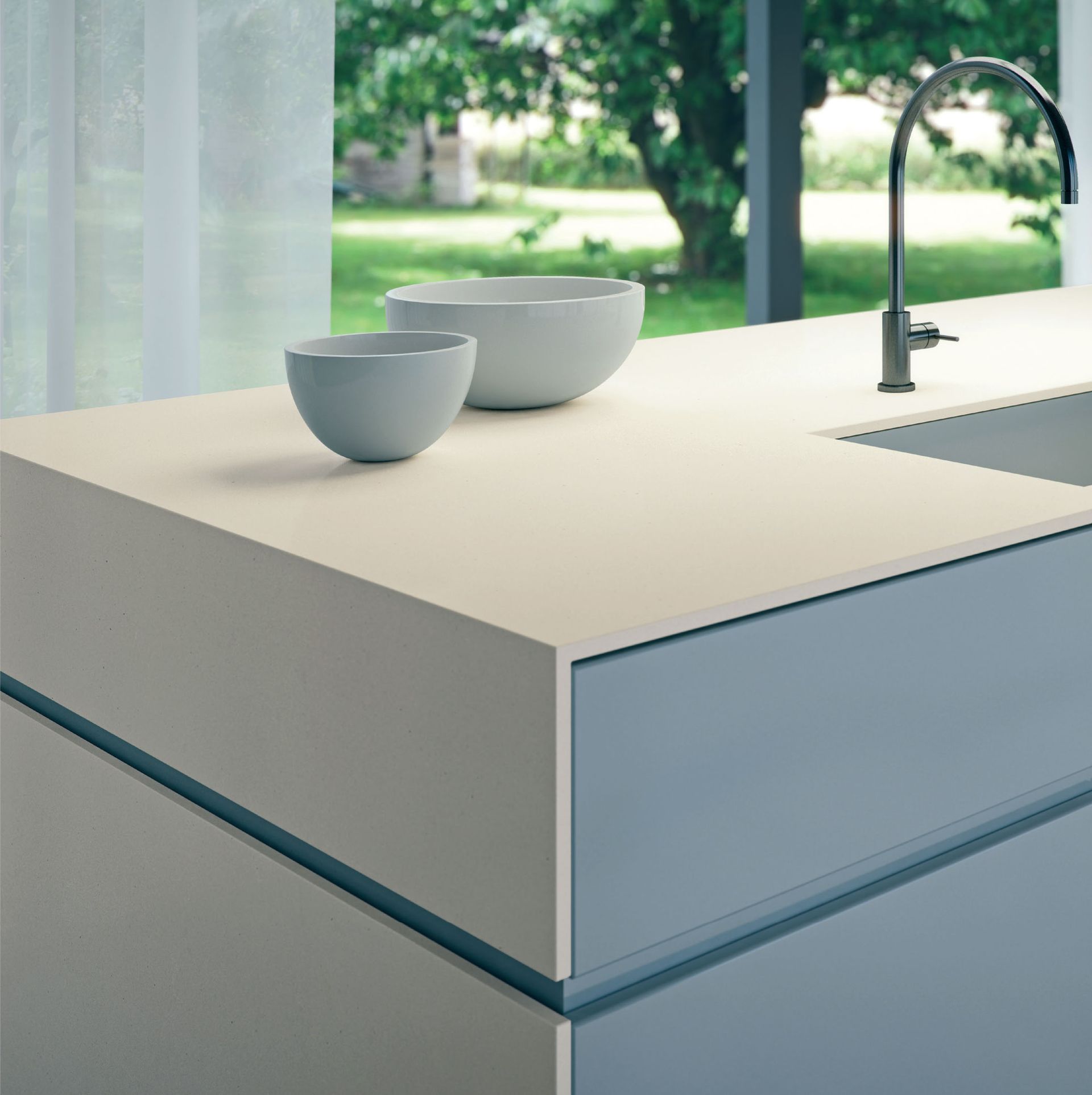 Modern kitchen island with a sink, chrome faucet, and two bowls near a window