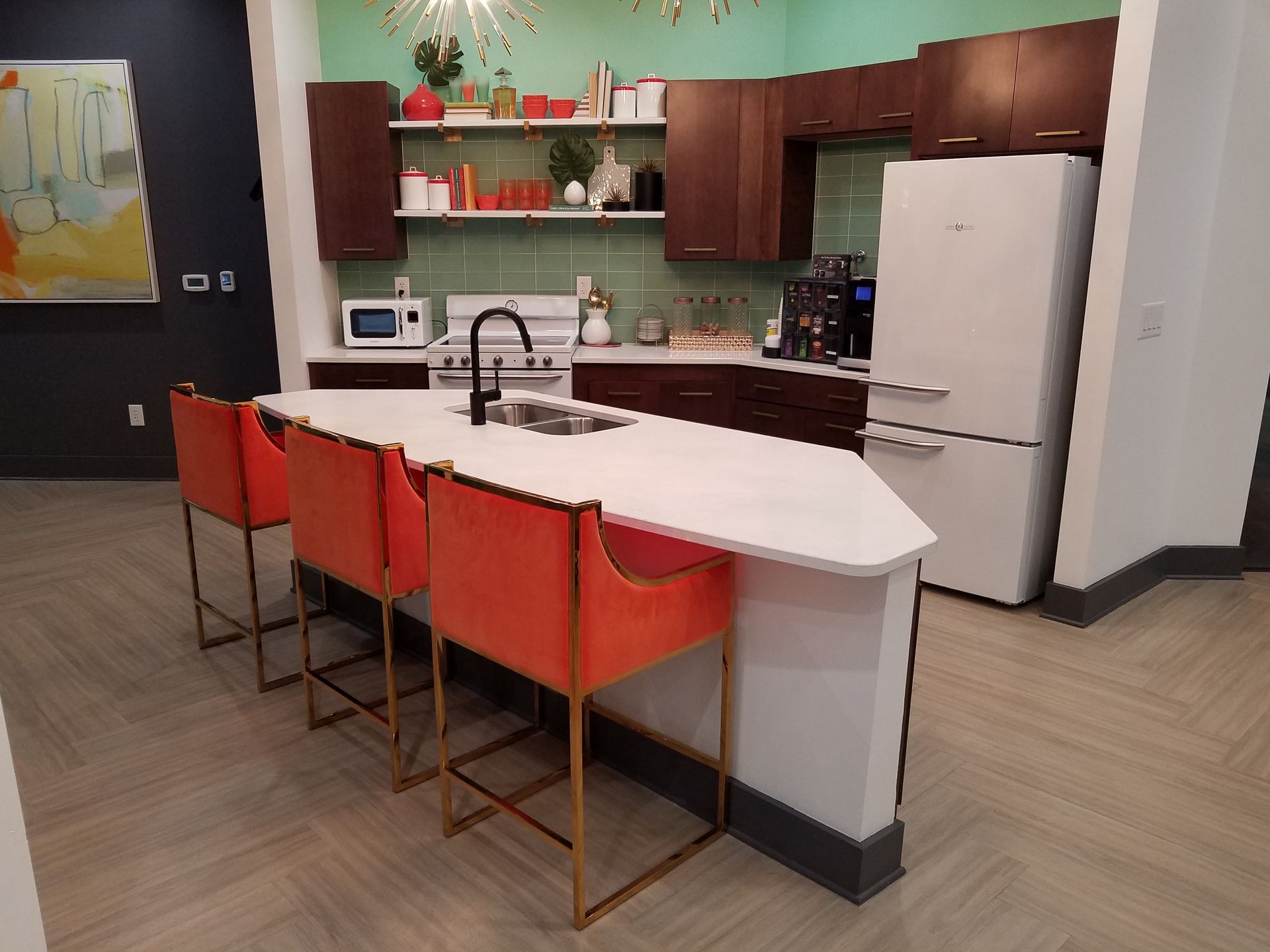 Modern kitchen with white island, orange bar stools, brown cabinets, and stainless fridge