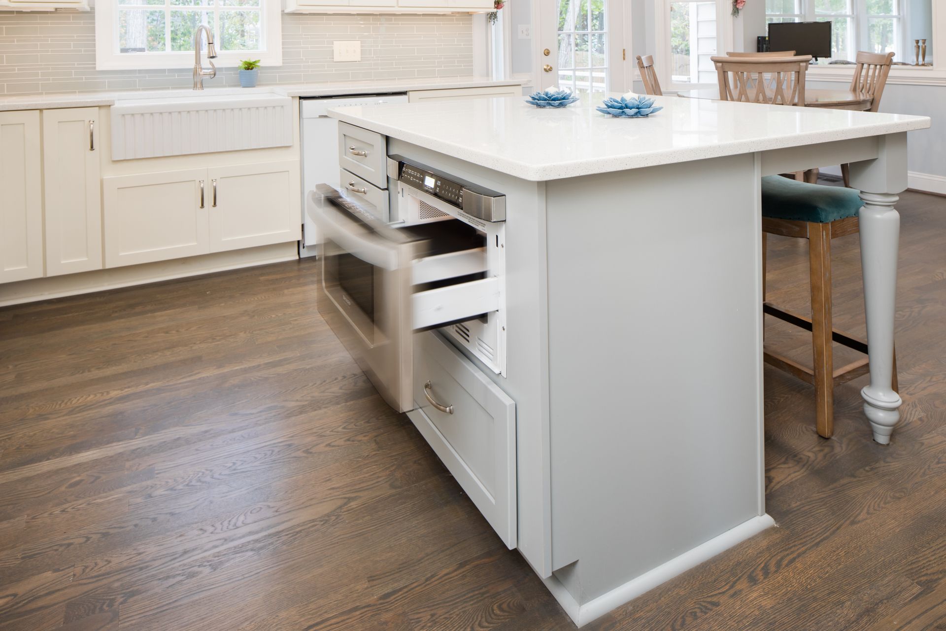 Bright modern kitchen with white island, wood floors, and a pull-out drawer open on the side