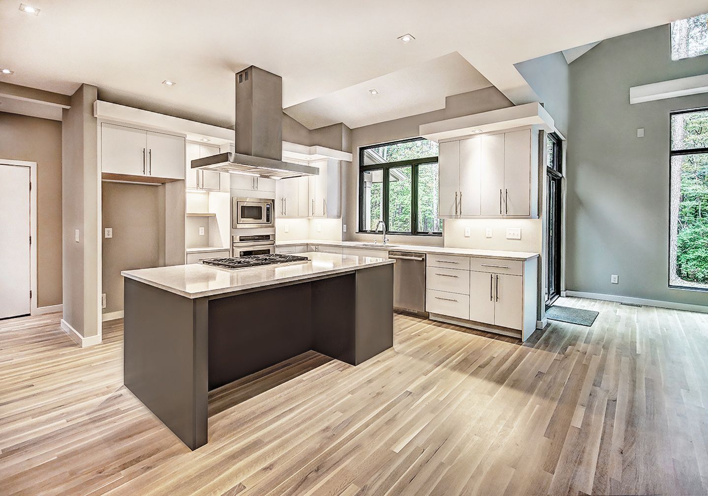 Bright modern kitchen with island, white cabinets, stainless appliances, and light wood floors