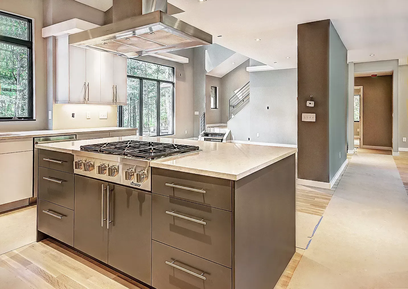 Modern kitchen with island, stainless range, white countertops, and large windows
