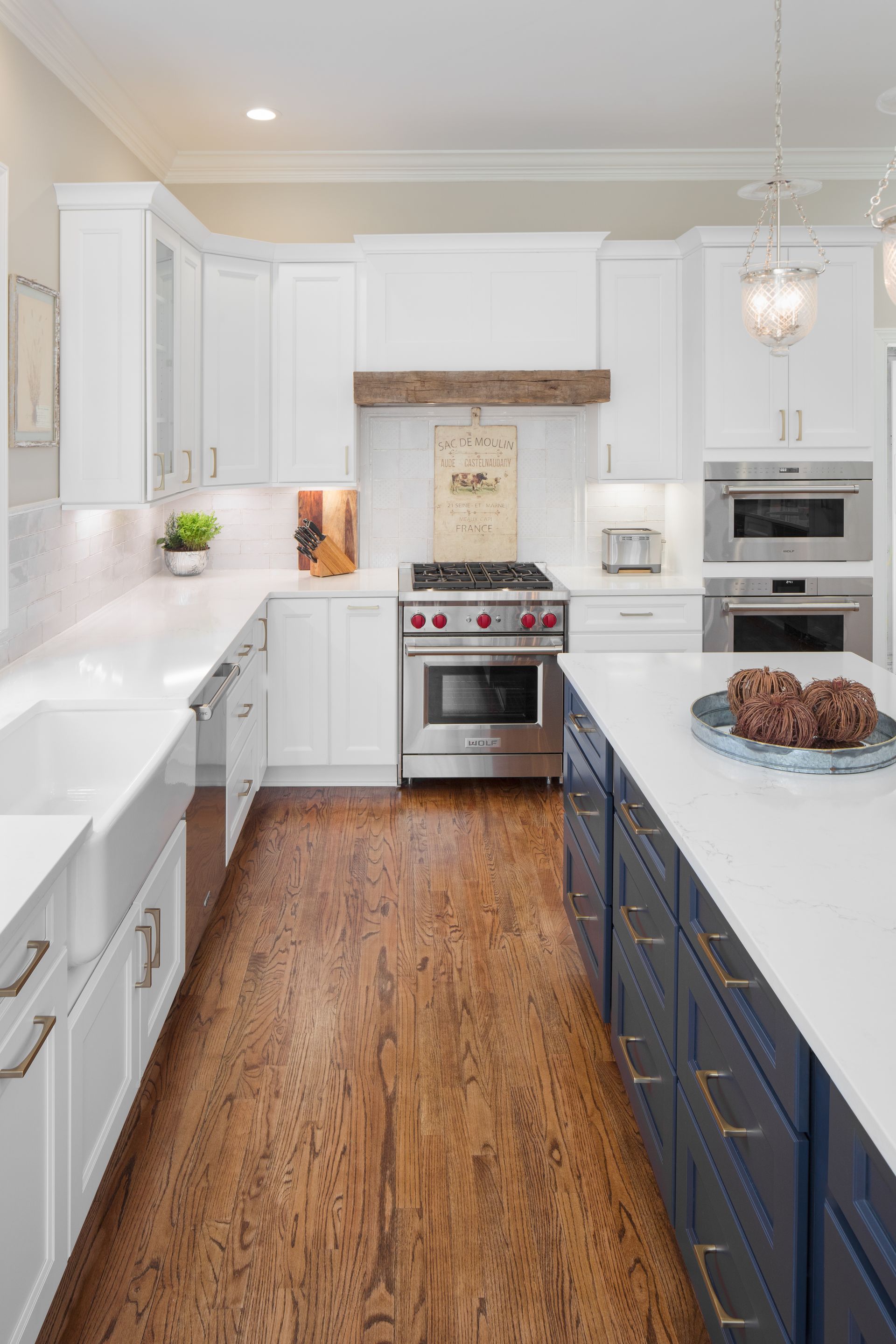Bright modern kitchen with white cabinets, navy island, stainless stove, and wood floor