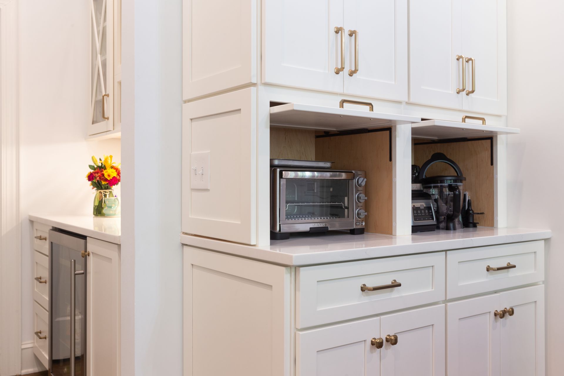 White built-in kitchen cabinets with a microwave and toaster oven in open shelves