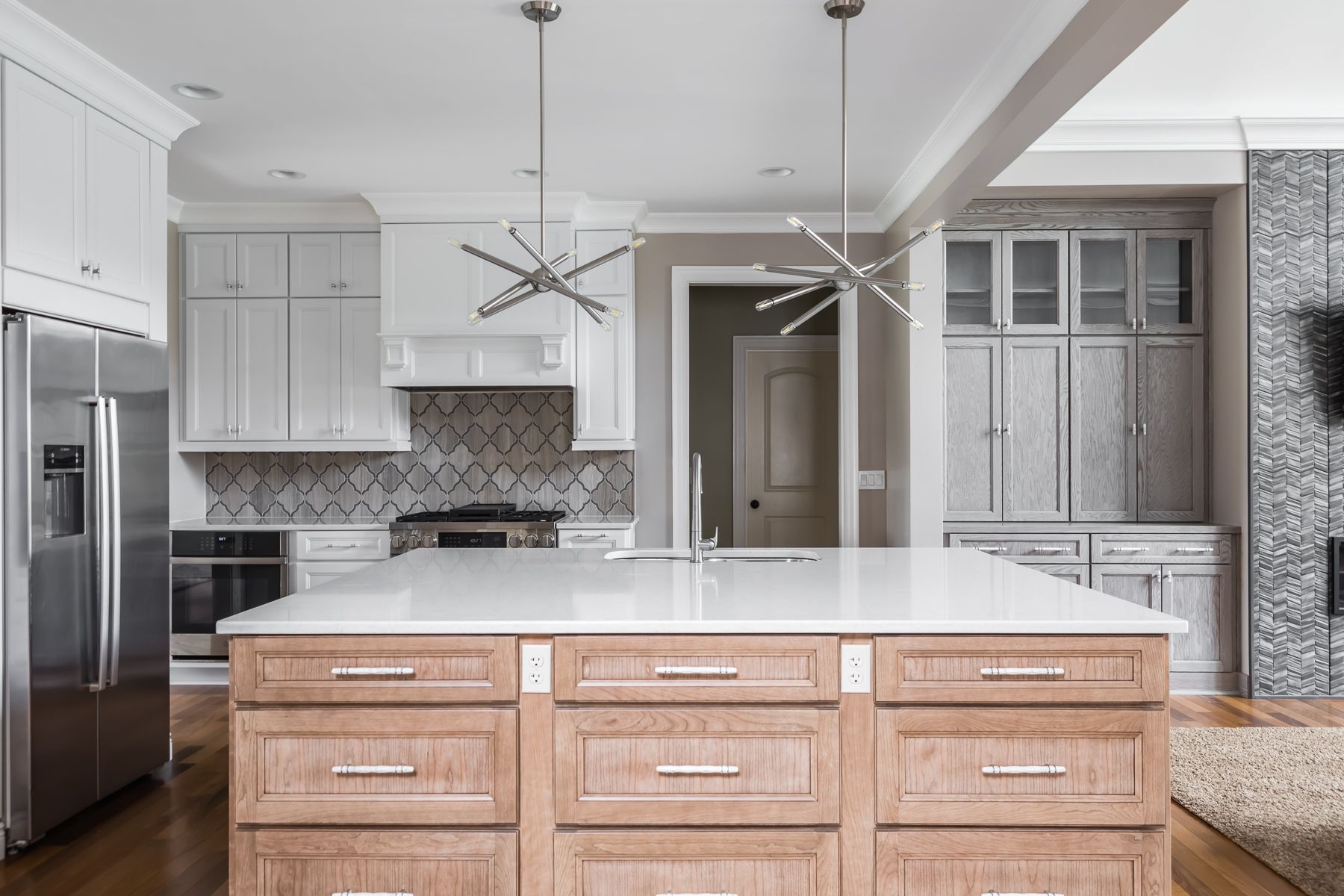 Modern kitchen with white cabinets, island, stainless steel fridge, and pendant lights