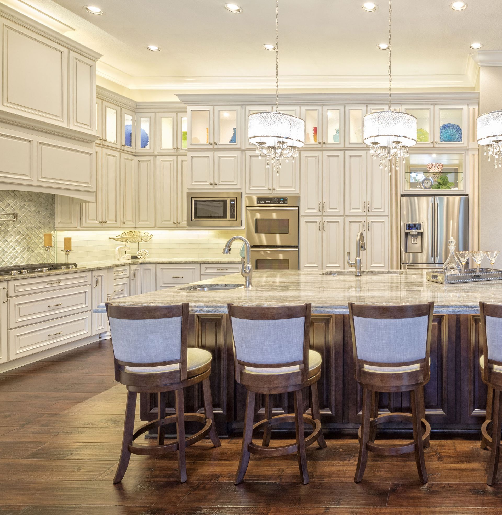 Bright, white gourmet kitchen with a large marble island and four barstools