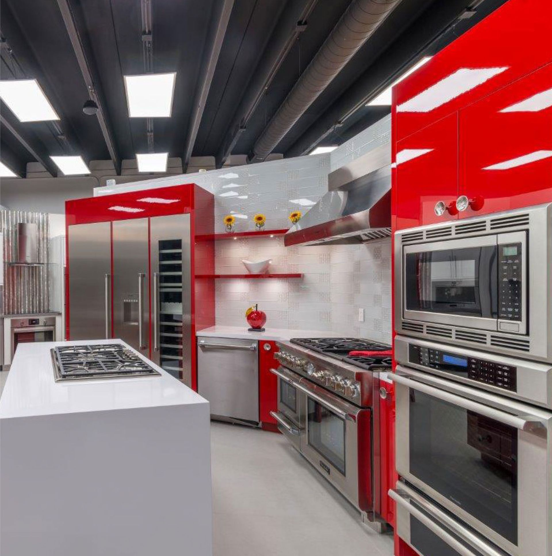 Modern red-and-stainless-steel kitchen with island, gas range, and built-in ovens