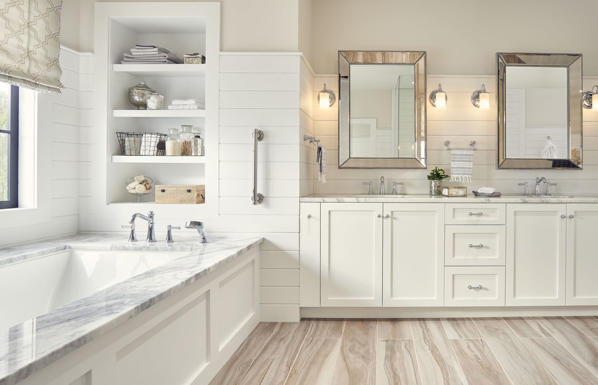 Bright white bathroom with marble vanity, tub, mirrors, and built-in shelving