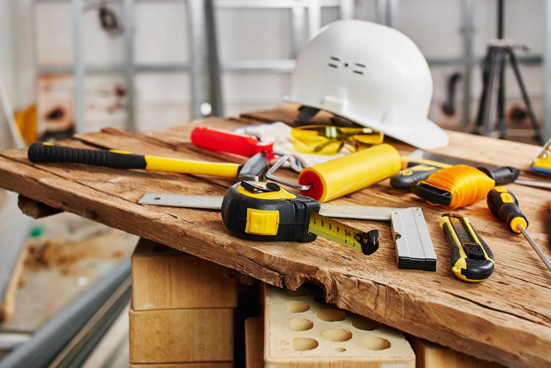 A hard hat is sitting on top of a wooden table with construction tools.