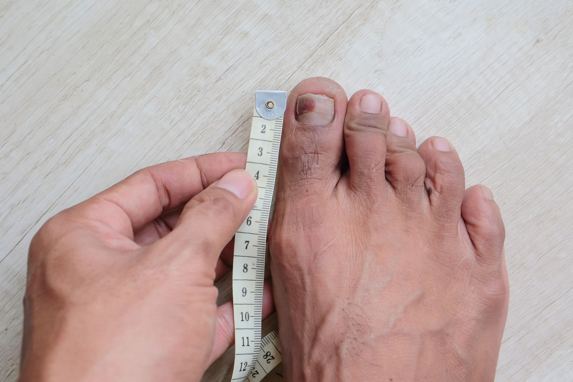 A person is measuring their foot with a tape measure.