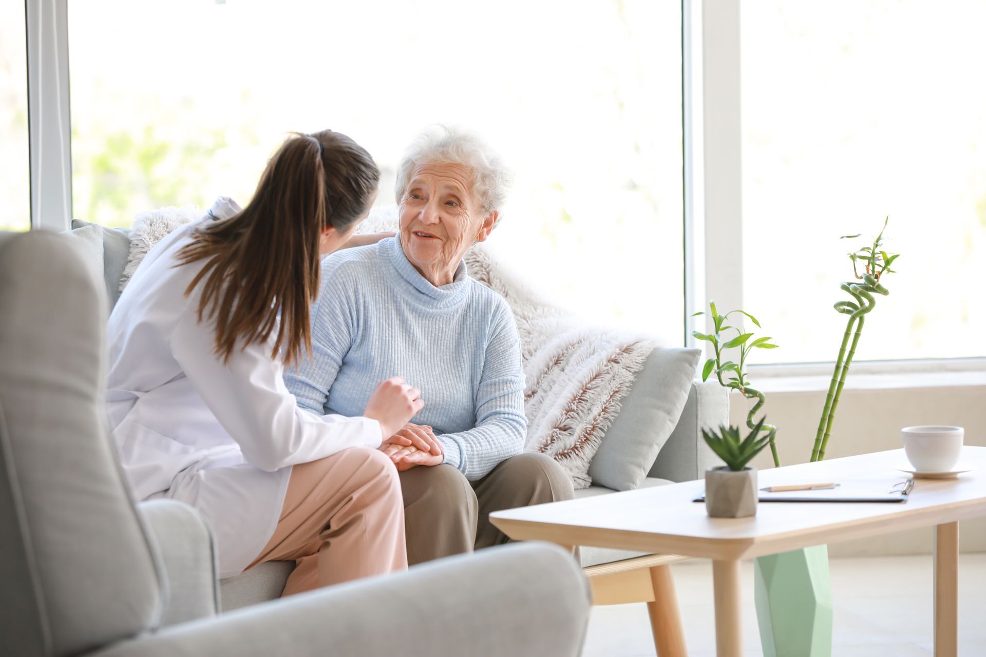 Elderly woman smiling with caregiver at home, receiving attentive home health care service.