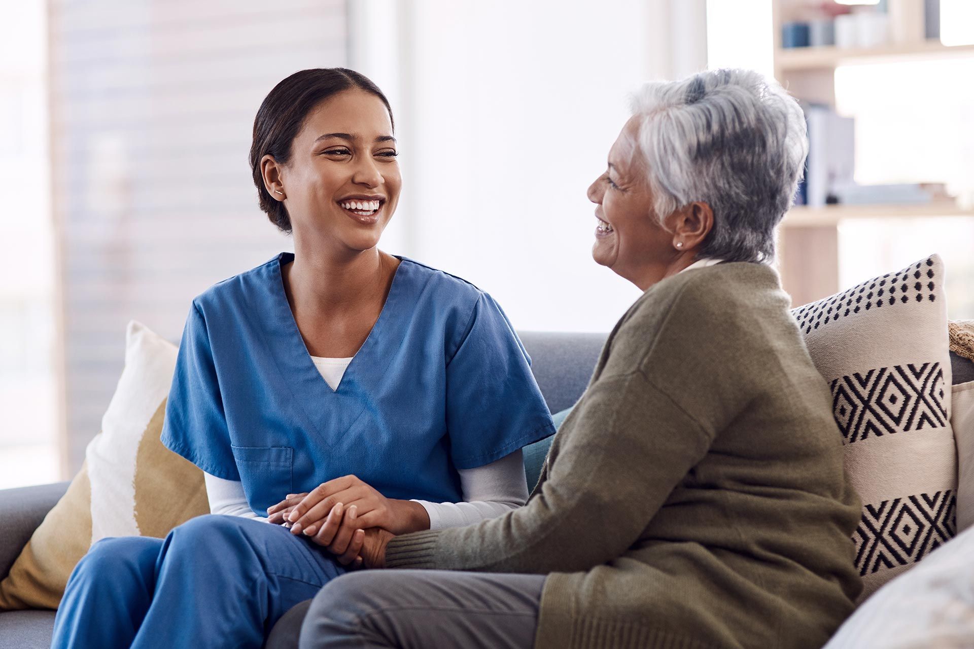 A senior woman and a caregiver are chatting, showcasing an in-home senior healthcare service.