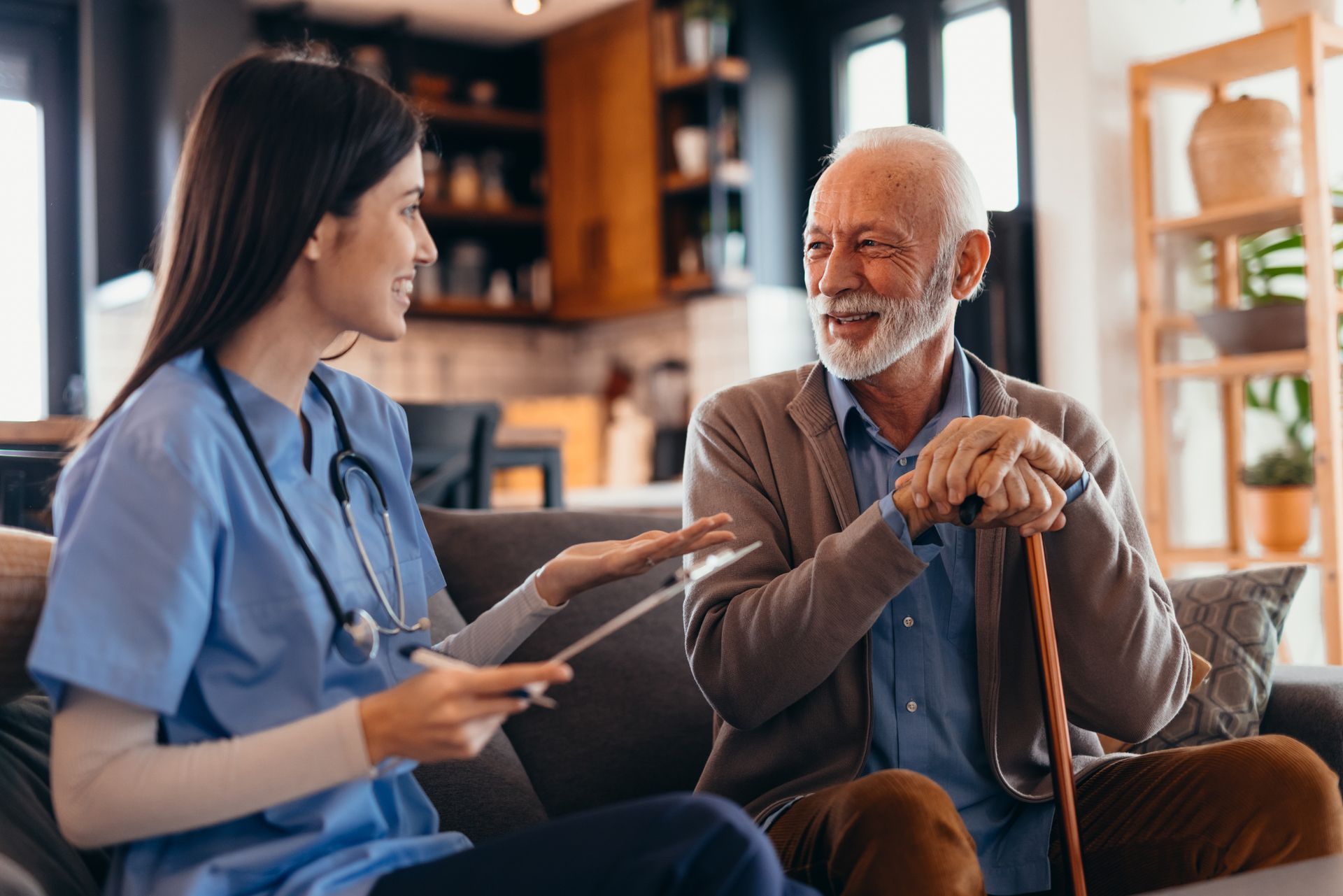 Healthcare worker talking to elderly person with a cane in a home setting