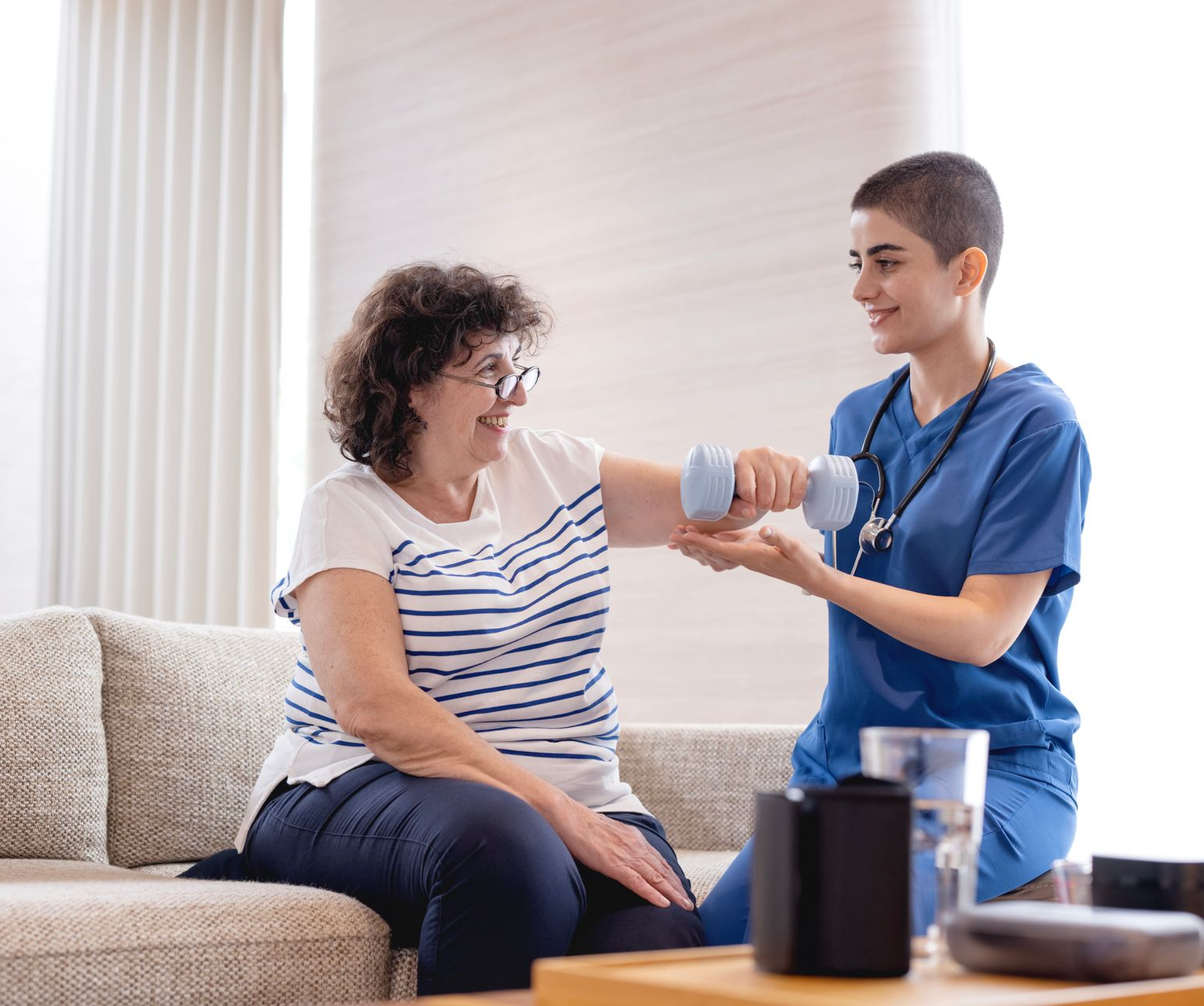 Healthcare professional assisting senior during in-home physical therapy session. Healthcare professional assisting senior during in-home physical therapy session.