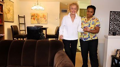 Elderly woman, with support, walking indoors with caregiver. Elderly woman, with support, walking indoors with caregiver.
