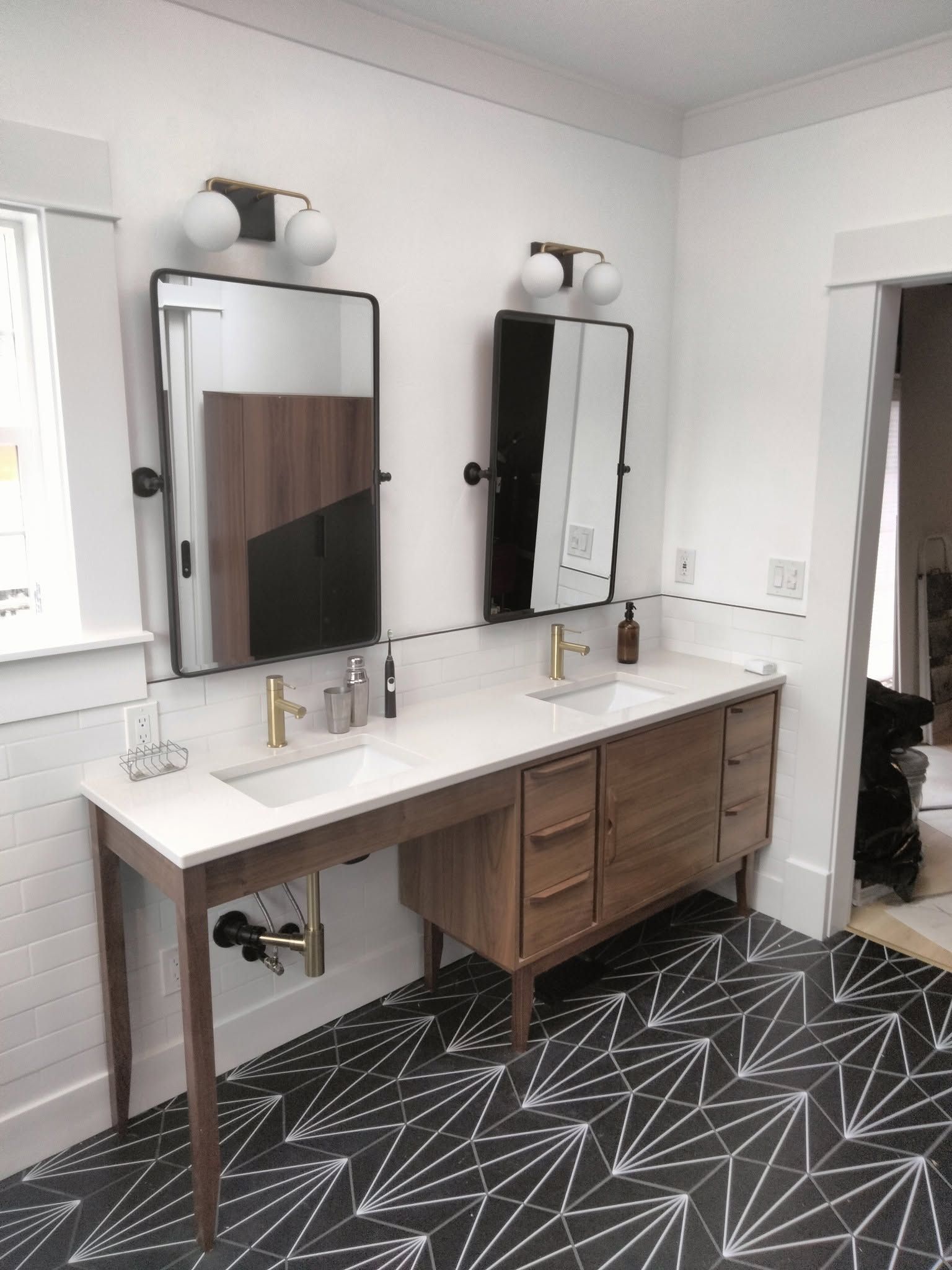 Modern bathroom vanity with two mirrors, double sinks, and dark patterned flooring