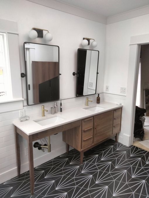 Modern bathroom vanity with two mirrors, double sinks, and dark patterned flooring