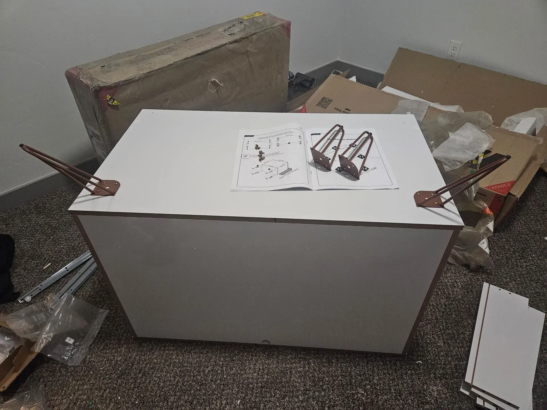 White cabinet or box in a cluttered room with papers and cardboard around it