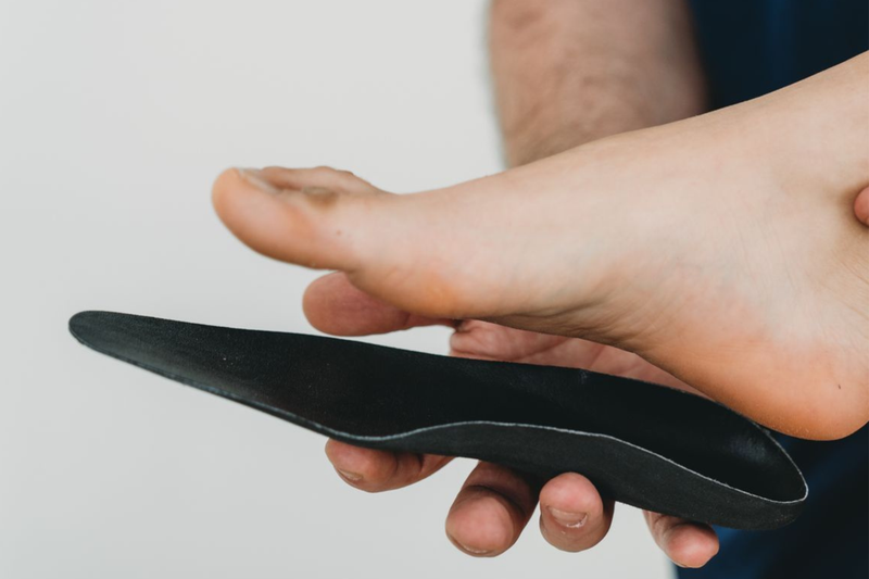 Un piede che preme una soletta nera sulla mano di una persona
