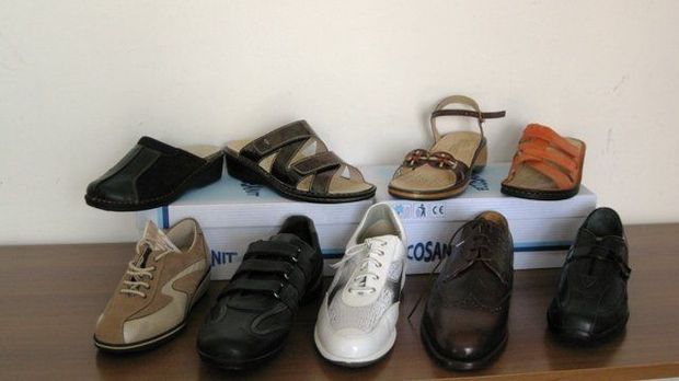 Sei paia di scarpe allineate su una superficie bianca, tra cui sandali, mocassini e scarpe eleganti.