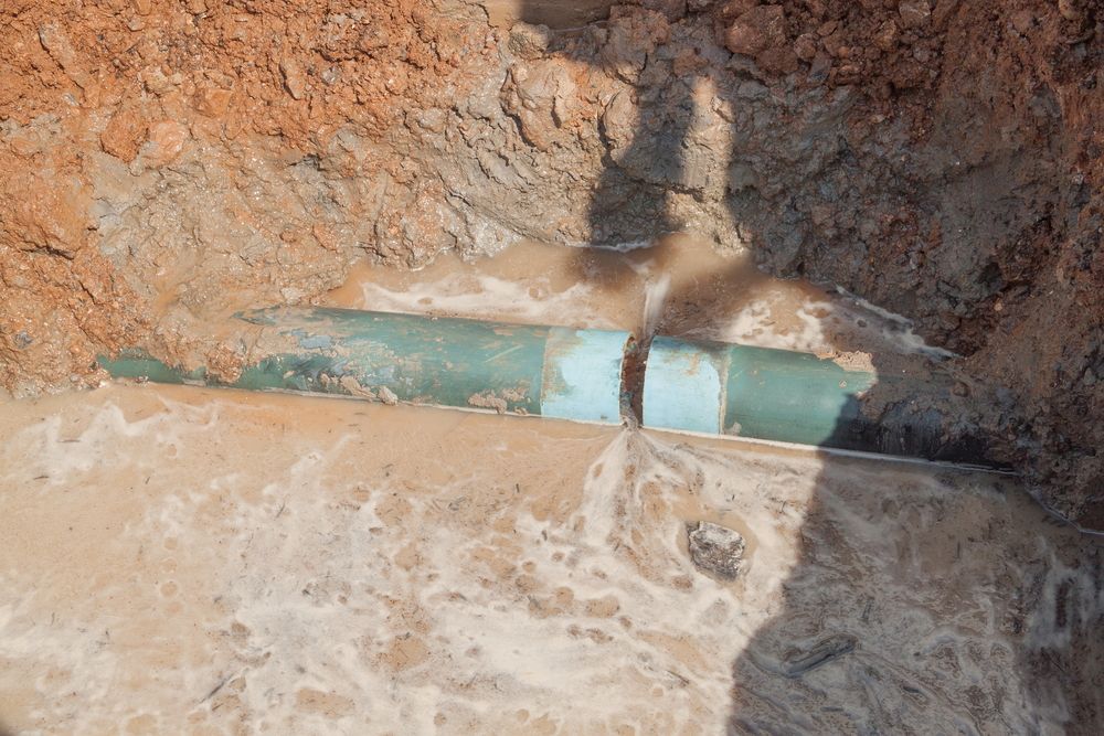 A Green Pipe Is Laying In The Dirt In A Hole — Sampson Plumbing Pty Ltd In Pottsville, NSW