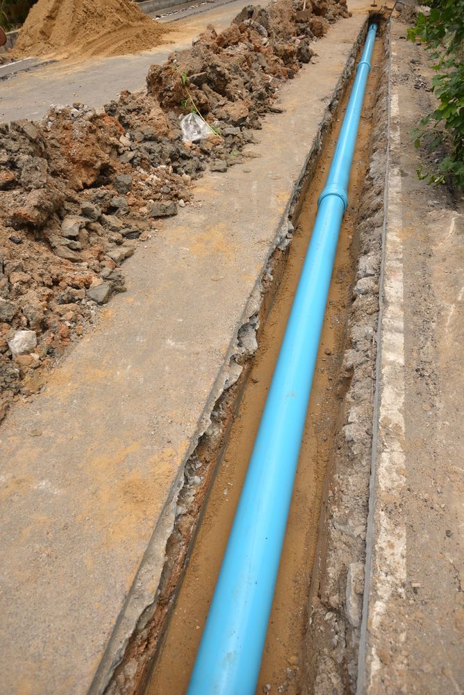 A Blue Pipe Is Being Installed In A Trench — Sampson Plumbing Pty Ltd In Kingscliff, NSW
