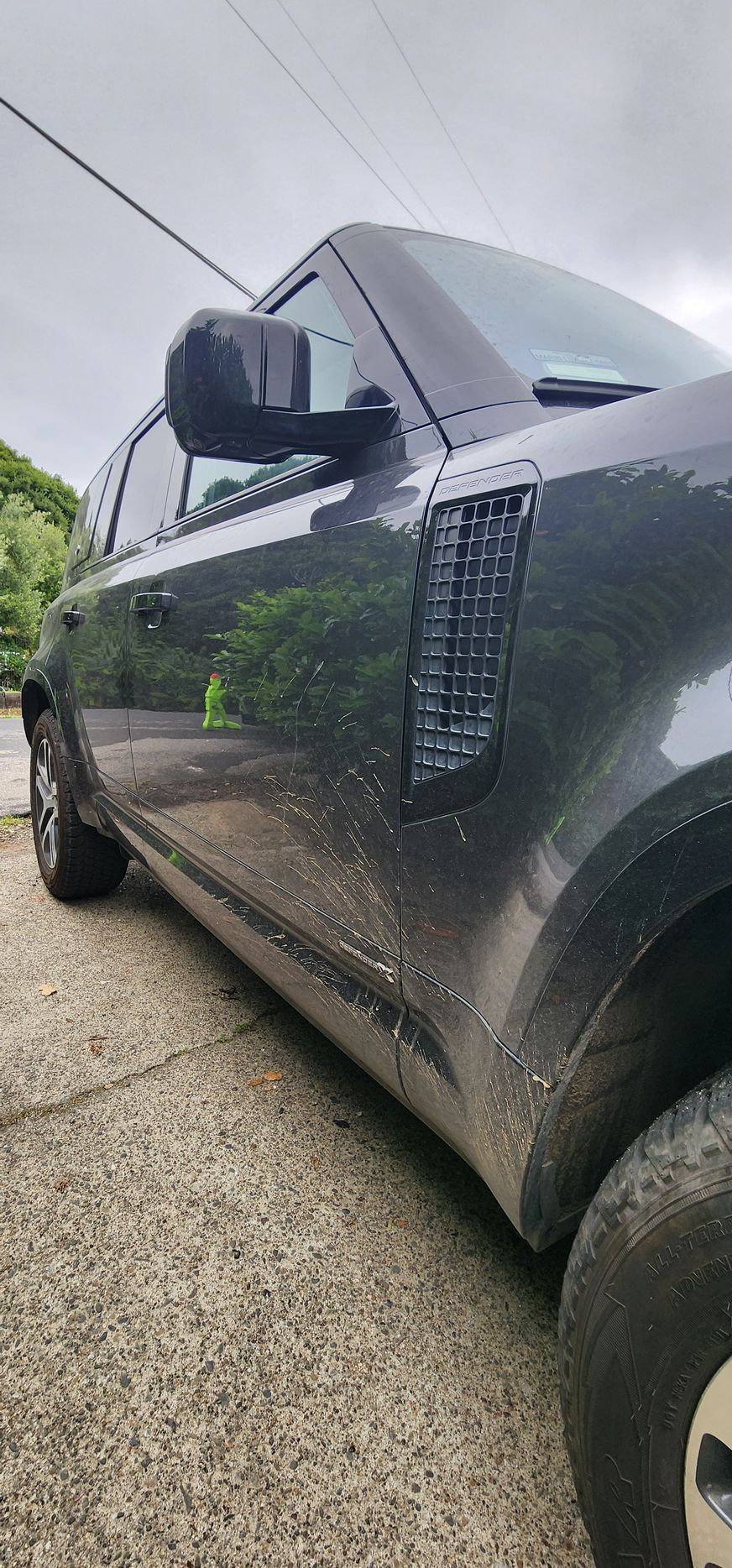 Close-up of a black SUV parked on a wet street, viewed from the side.