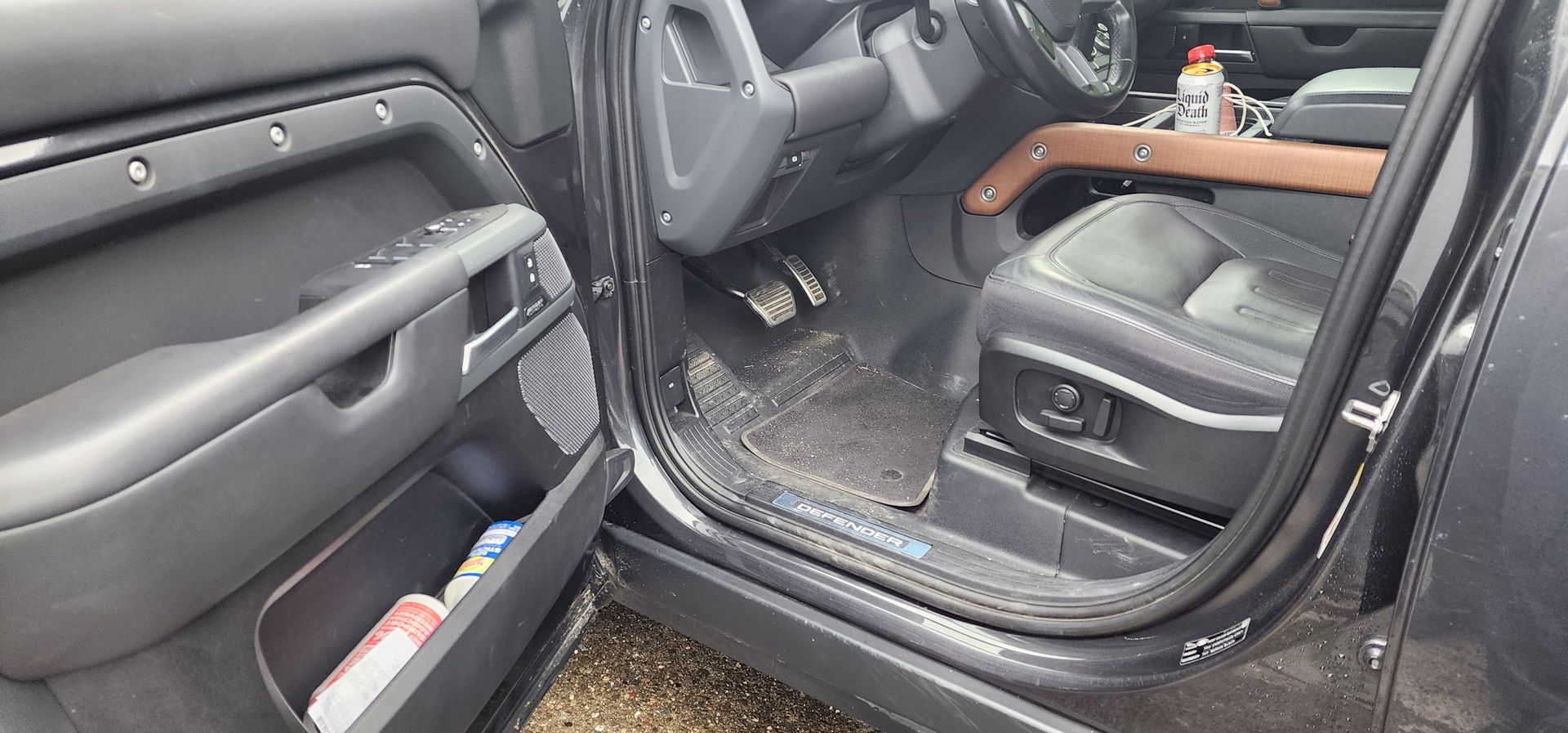 Black truck rear interior with open door, leather seats, and dirty floor mats