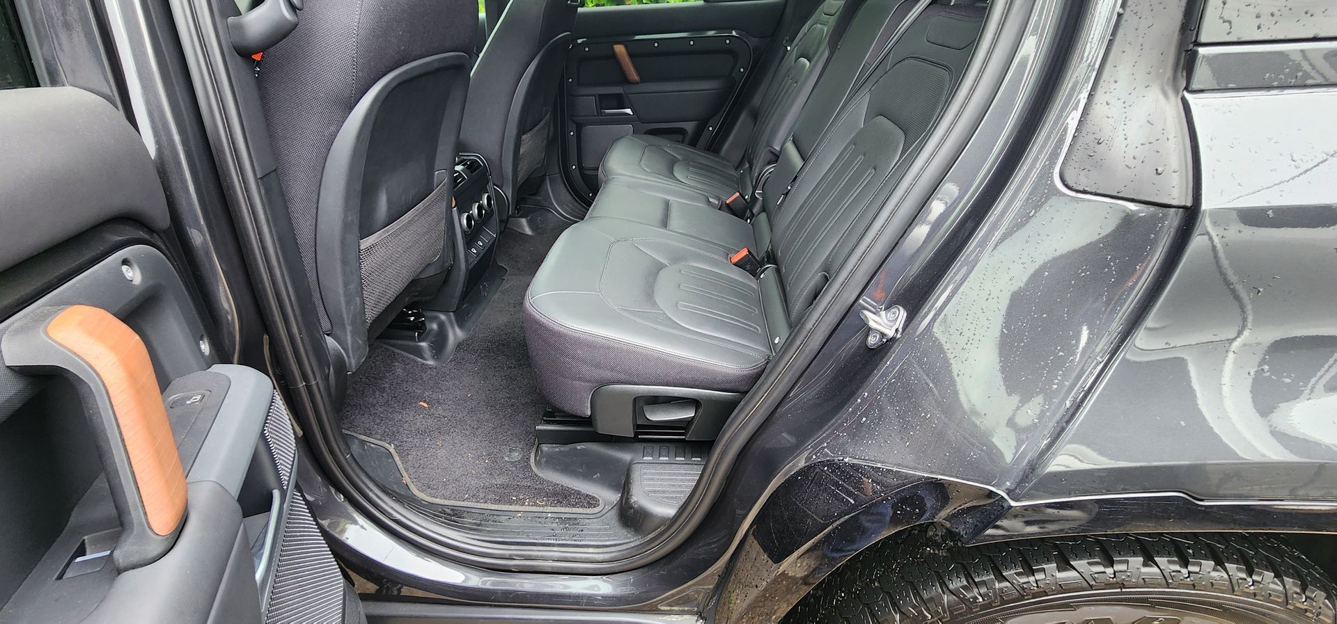 Open car rear seat with a gray interior and muddy floor mats