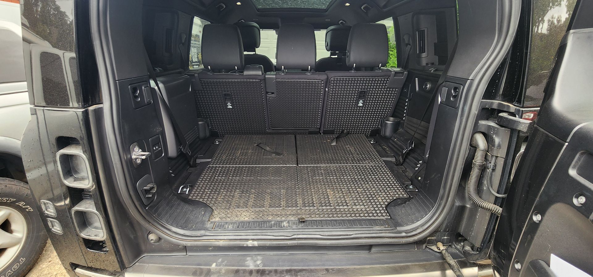 Open SUV cargo area with folded seats and a textured rubber floor mat
