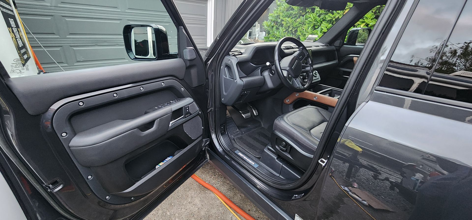 Black car with driver door open, showing the front seat and dashboard inside.