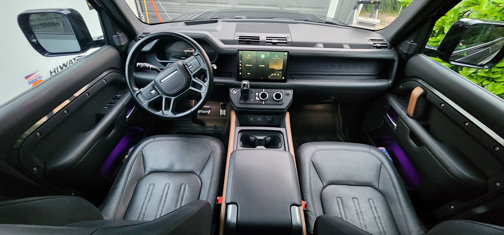 Luxury car interior with black leather seats, dashboard display, and purple ambient lighting