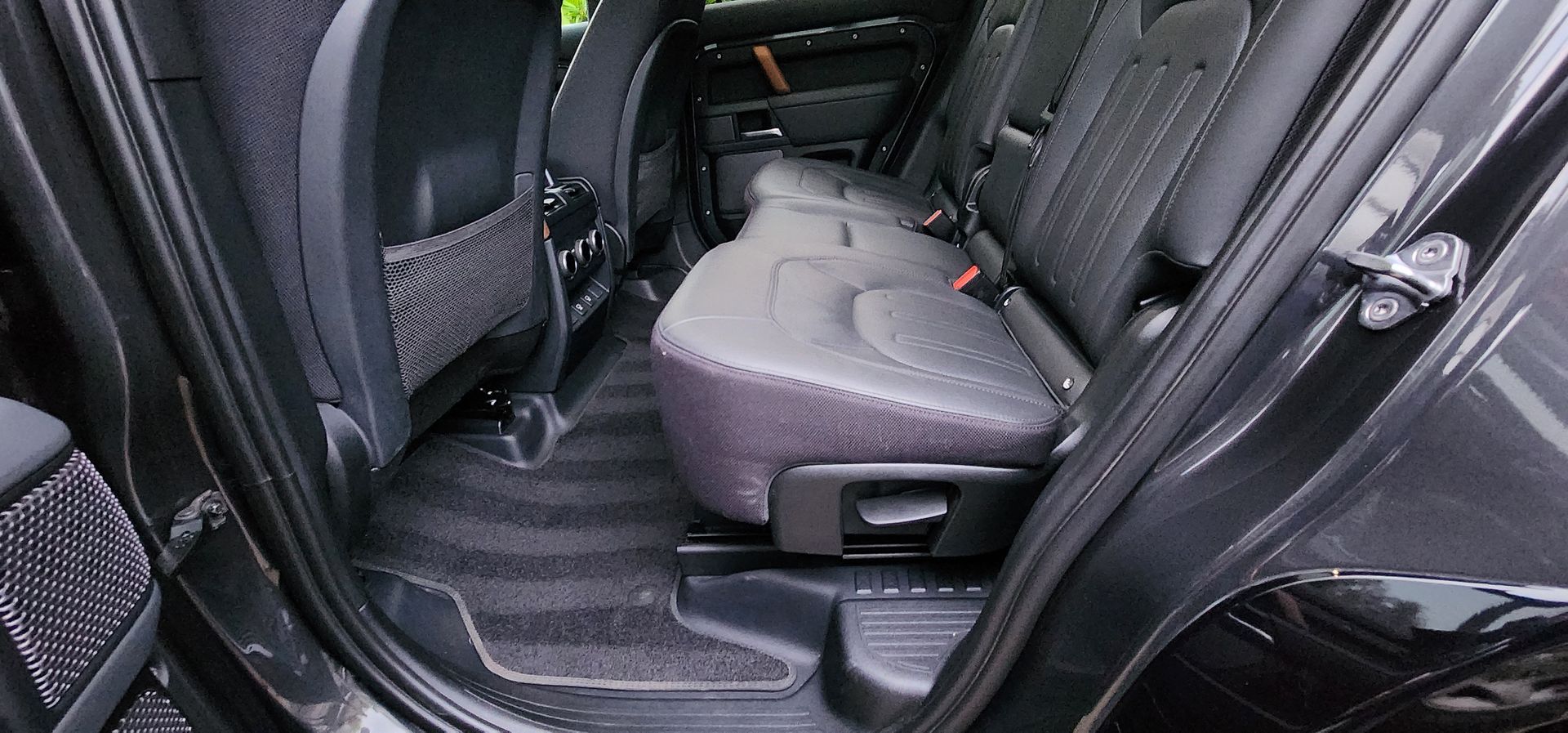 Car interior with rear seats folded down, showing a grey cushioned mat or seat cover in the back area.