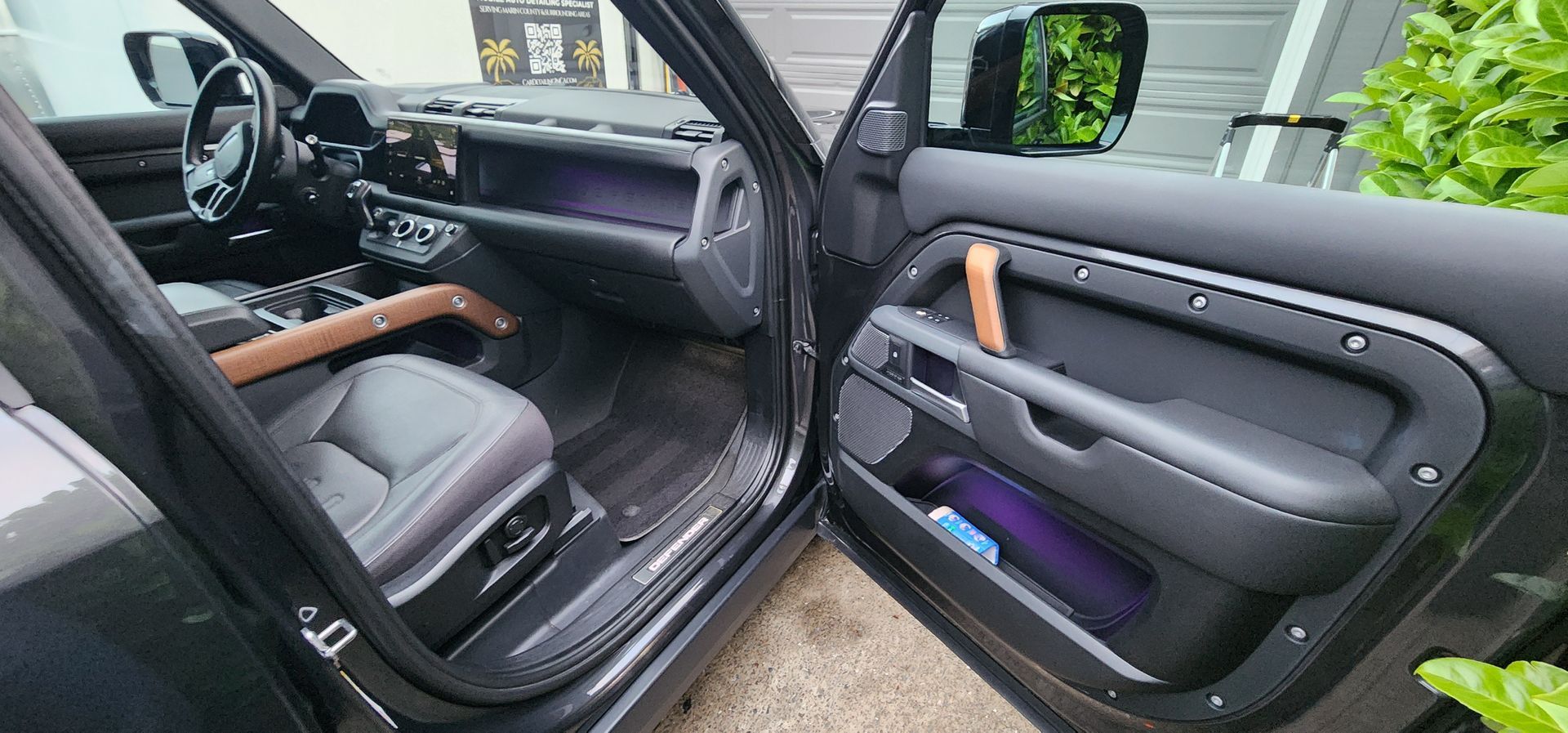 Open car doors reveal a black leather interior with wood accents and purple ambient lighting