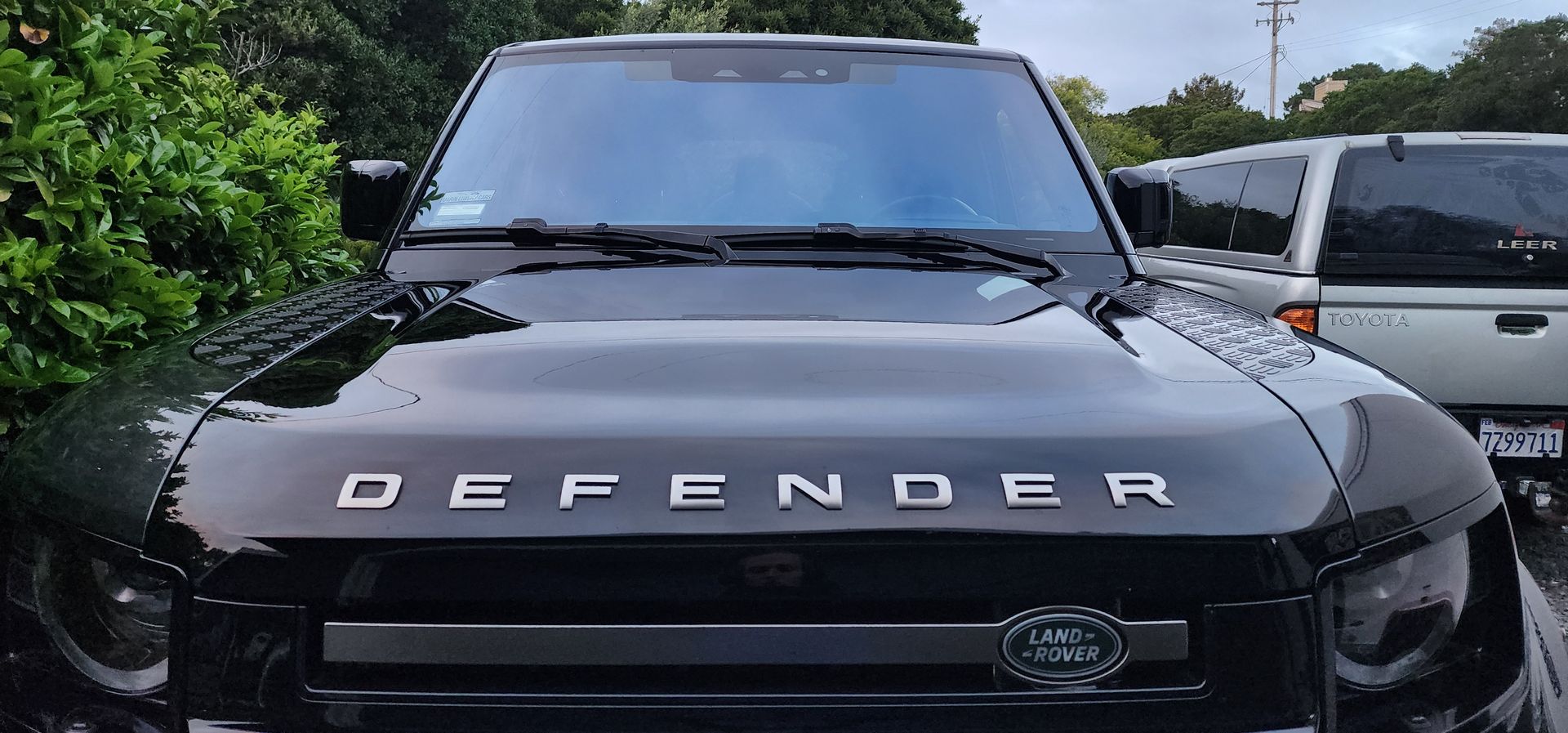 Black Land Rover Defender front view parked outdoors on a rainy day