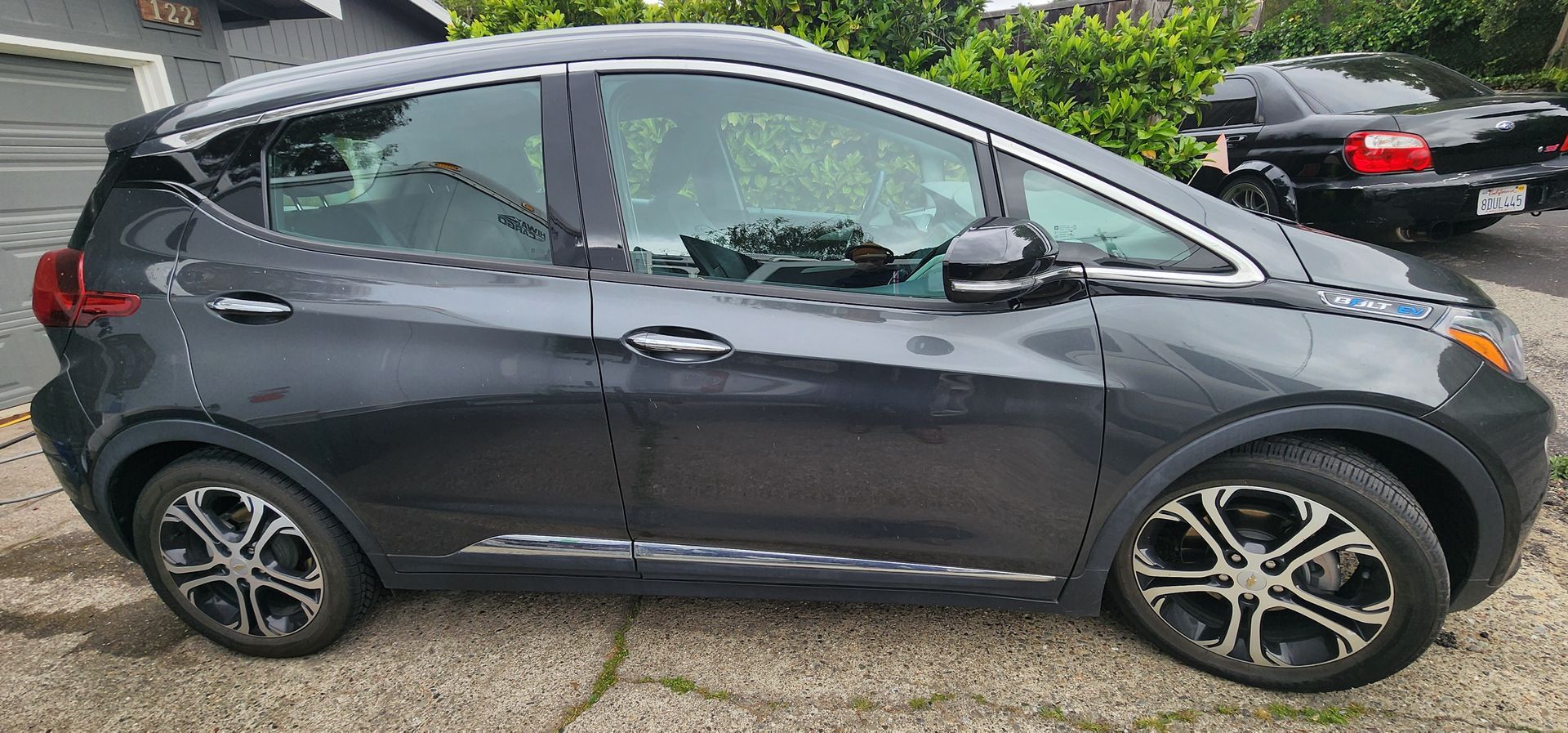Dark gray compact SUV parked on a wet street, side view