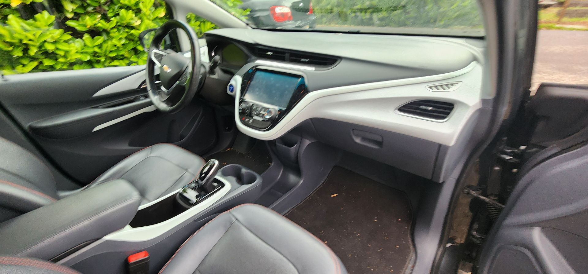 Car interior with black seats, white dashboard accents, steering wheel, and center console view