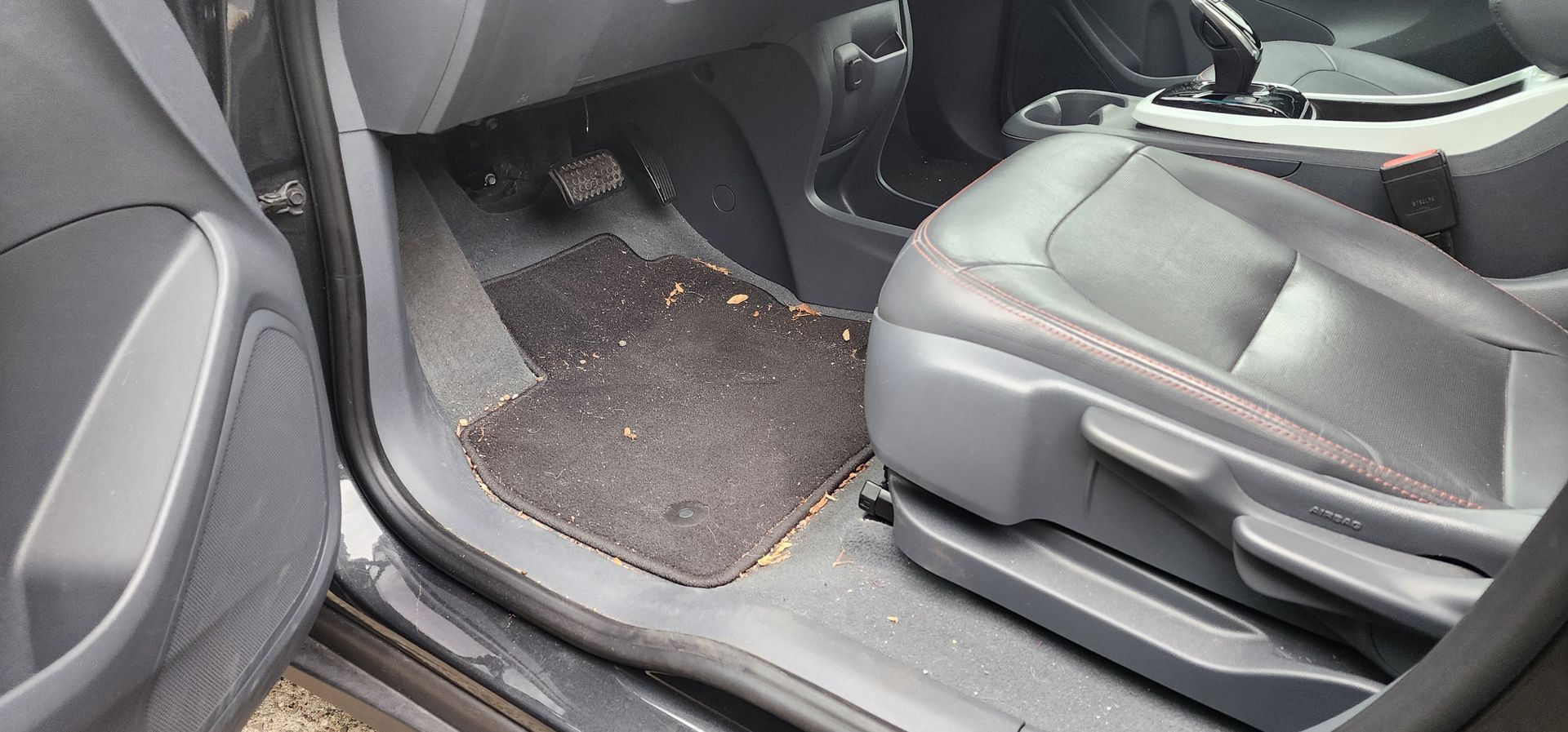 Car interior with open door, black floor mat, and gray front passenger seat.