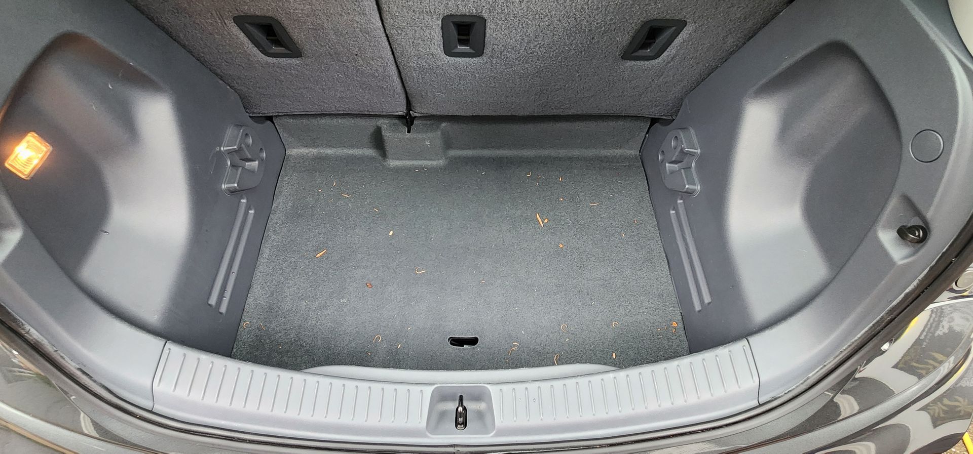Open car trunk with gray carpeted cargo area and folding rear seats