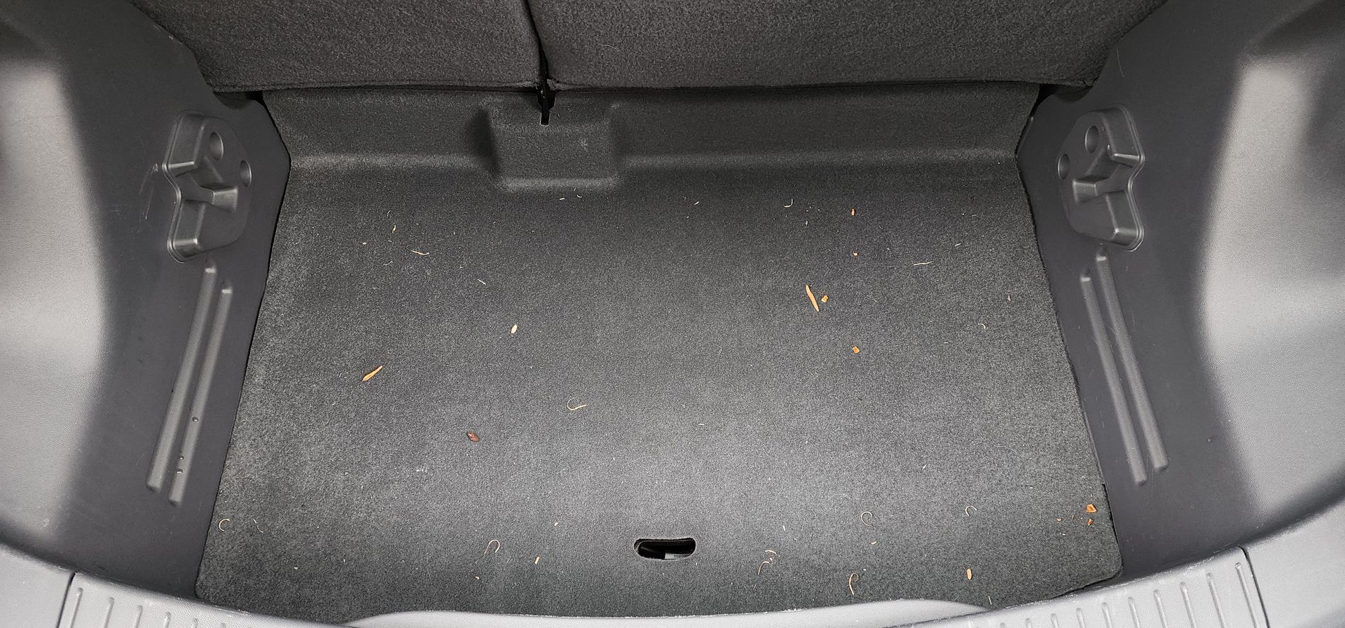 Car trunk interior with gray carpeted floor and side panels, empty and open.