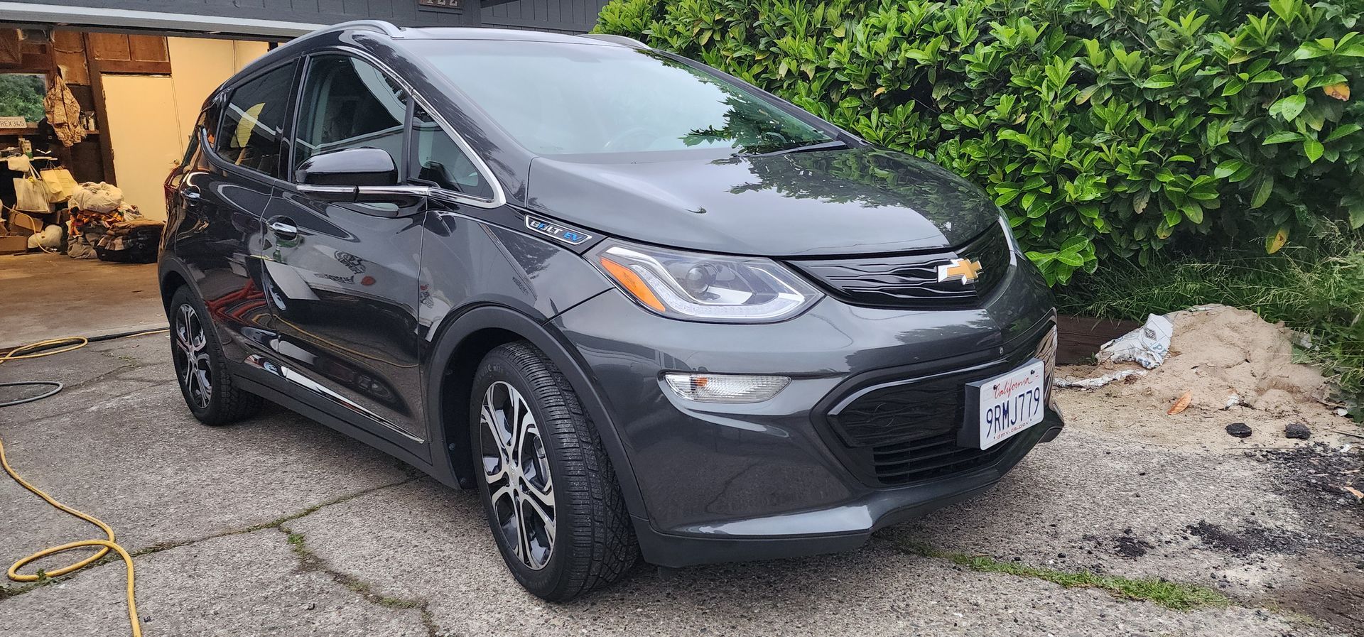 Dark gray compact SUV parked on a gravel driveway beside green hedges.
