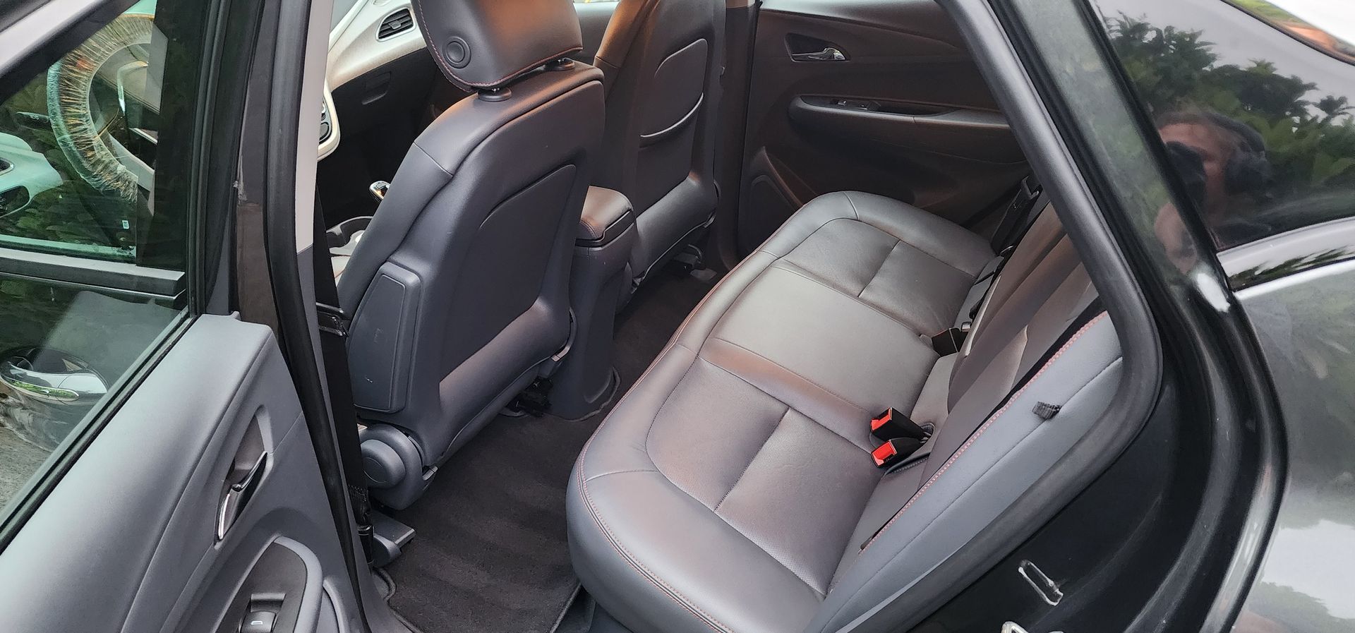 Open car rear seat with gray leather upholstery and a child car seat installed on the right.